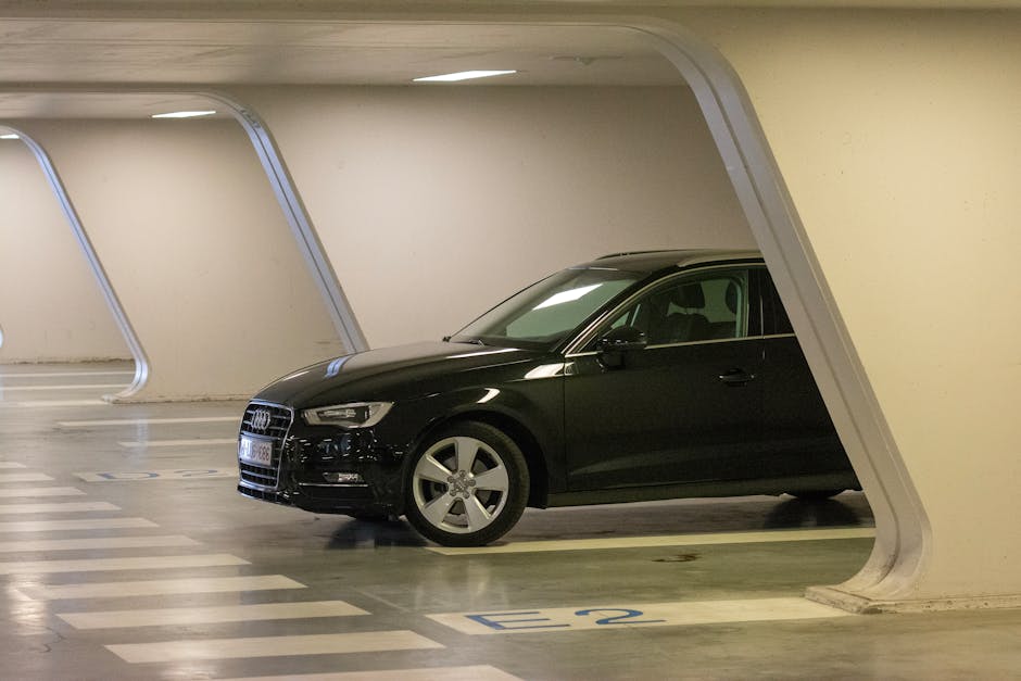 Black Audi sedan parked in a modern underground apartment garage showing the tight low-clearance structure